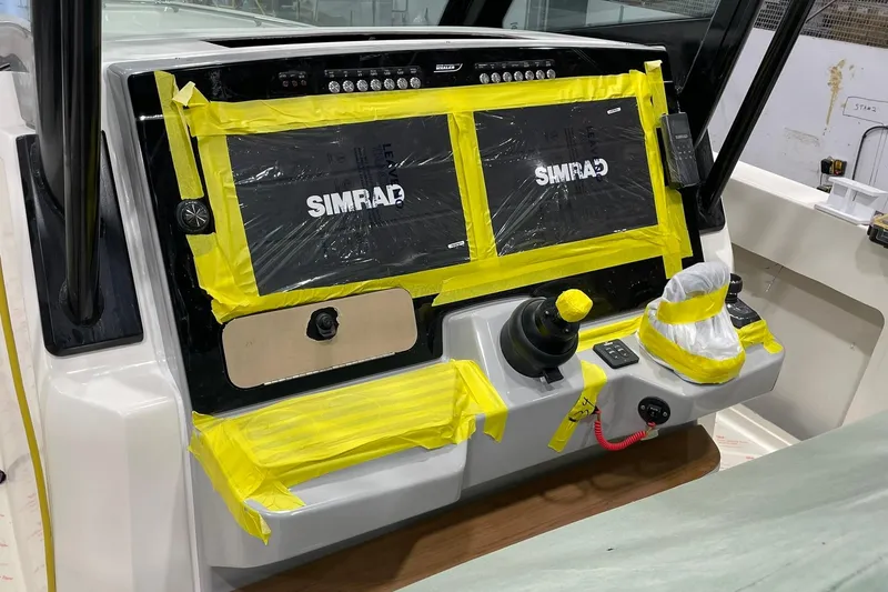 Slide: The Image of 2024 Boston Whaler 360 Outrage dashboard with Simrad displays, partially covered in protective tape. - 57
