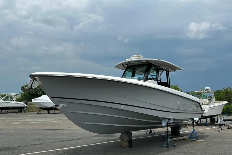 Slide: The Image of 2024 Boston Whaler 360 Outrage boat on stands under cloudy sky. - 85