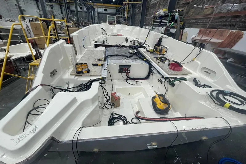 Slide: The Image of 2024 Boston Whaler 360 Outrage under construction in a workshop, showcasing interior wiring and components. - 45