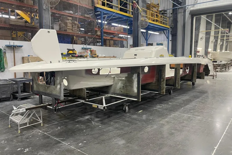 Slide: The Image of 2024 Boston Whaler 360 Outrage boat under construction in a factory setting. - 48
