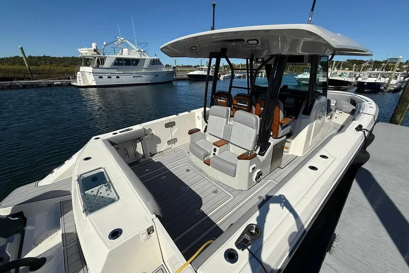 Slide: The Image of 2024 Boston Whaler 360 Outrage boat docked, showcasing spacious deck and seating. - 8