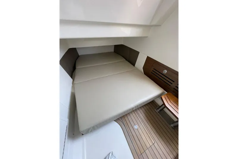 Slide: The Image of 2024 Boston Whaler 360 Outrage cabin interior with cushioned bed and wooden flooring. - 80