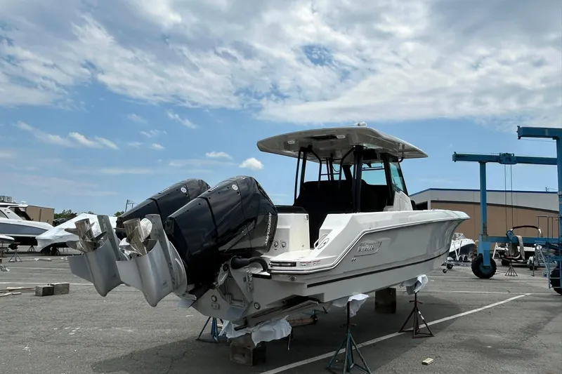 Slide: The Image of 2024 Boston Whaler 360 Outrage boat with dual outboard engines in a marina setting. - 88