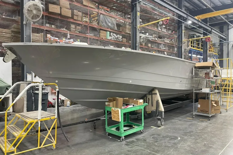 Slide: The Image of 2024 Boston Whaler 360 Outrage boat under construction in a factory setting. - 47