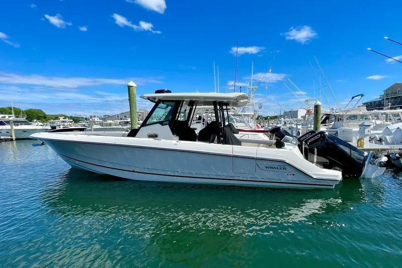 Slide: The Image of 2024 Boston Whaler 360 Outrage boat docked in a marina under a clear blue sky. - 2