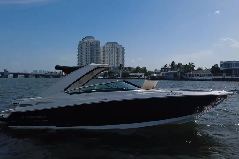 Slide: The Image of 2011 Monterey 328SS Super Sport boat cruising near waterfront buildings under a clear blue sky. - 8
