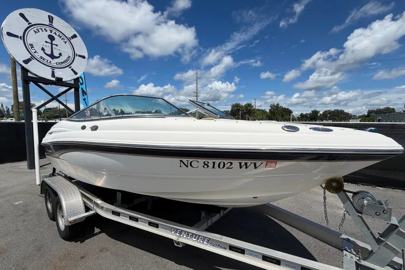 The Image of A 2003 Chaparral 183 SS boat on a trailer, in front of a sign with an anchor logo. - 0