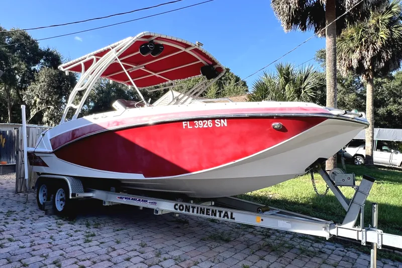 The Image of 2019 Glastron GTD 220 boat on trailer, red and white design, parked outdoors. - 0