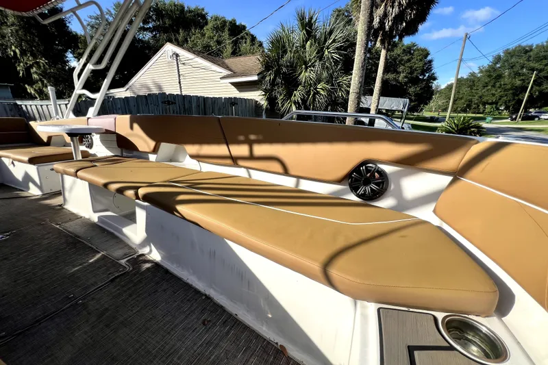 Slide: The Image of 2019 Glastron GTD 220 boat interior with tan seating and speaker, outdoor setting. - 43