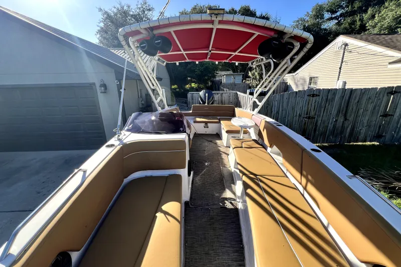Slide: The Image of 2019 Glastron GTD 220 boat with tan seating and red canopy in a residential driveway. - 34