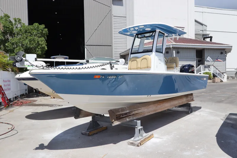 The Image of 2022 Sportsman Masters 247 Bay Boat in a marina setting, blue hull, on display. - 0