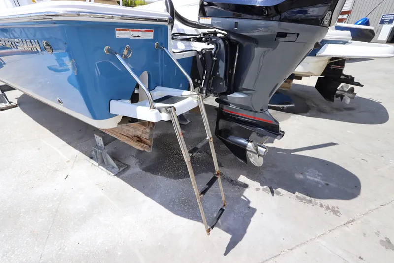 Slide: The Image of 2022 Sportsman Masters 247 Bay Boat with ladder and outboard motor in a marina. - 6