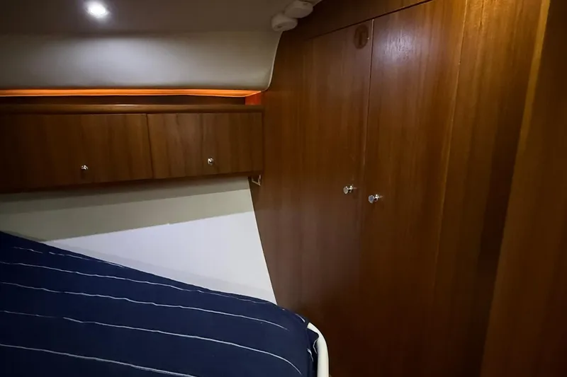 Slide: The Image of 2011 Tiara Yachts 4500 Sovran cabin interior with wooden cabinetry and striped bedding. - 52