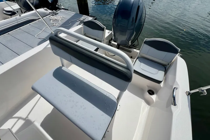 Slide: The Image of 2025 Robalo R160 Center Console boat interior with seating and motor, docked on water. - 6