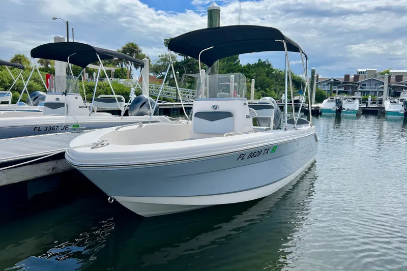 Slide: The Image of 2025 Robalo R160 Center Console boat docked in a marina under a cloudy sky. - 3