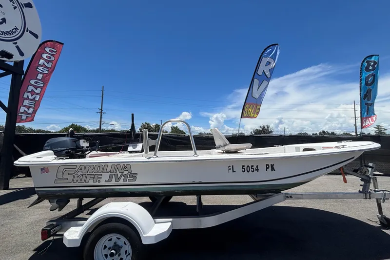 Slide: The Image of Un bote Carolina Skiff JV15TH en un remolque, rodeado de banderas de venta. - 1