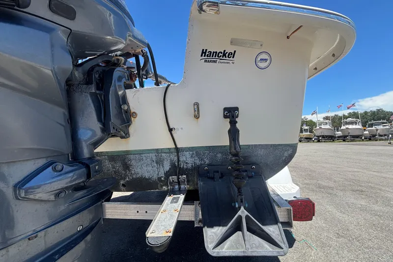 Slide: The Image of 2010 Carolina Skiff JV15TH boat stern with motor and trim tabs in a marina setting. - 3