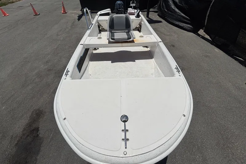 Slide: The Image of 2010 Carolina Skiff JV15TH boat on pavement, featuring open deck and seating. - 12