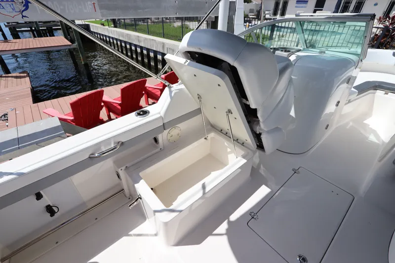 Slide: The Image of 2021 Robalo R227 Dual Console boat interior with open storage compartment, dockside view. - 13