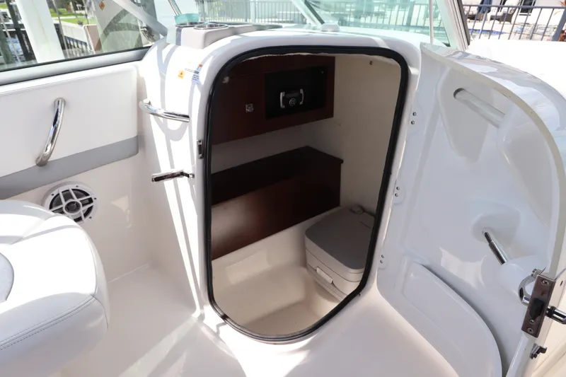 Slide: The Image of 2021 Robalo R227 Dual Console boat interior with storage compartment and portable toilet. - 14