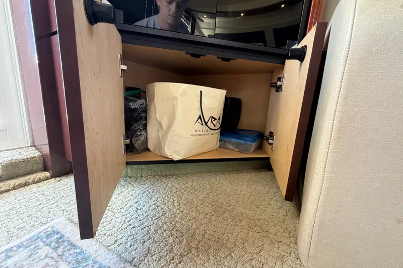 Slide: The Image of Open cabinet on 2010 Sea Ray 390 Sedan Bridge, showing storage with bags and containers. - 88