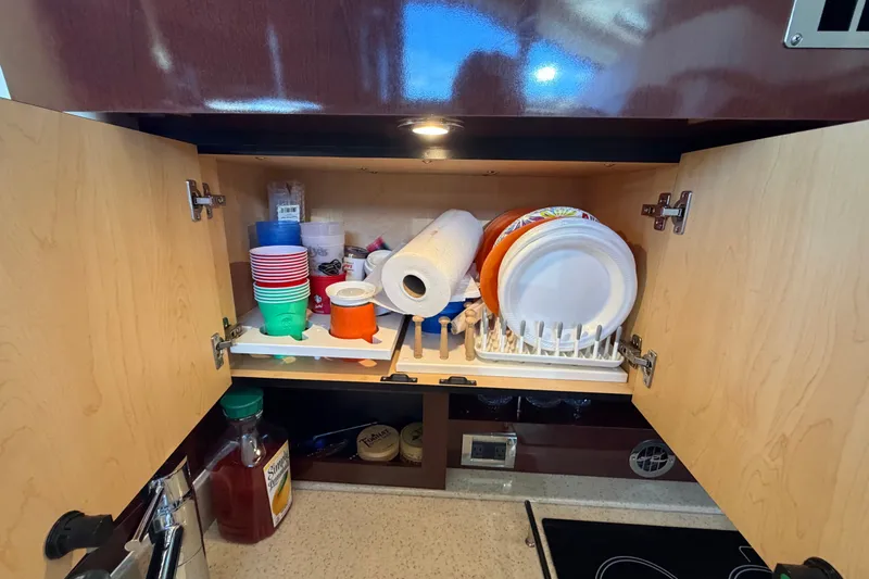 Slide: The Image of Open cabinet on 2010 Sea Ray 390 Sedan Bridge with cups, plates, and paper towels. - 74