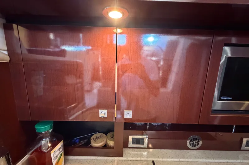 Slide: The Image of Interior of 2010 Sea Ray 390 Sedan Bridge with wooden cabinets and kitchen appliances. - 73
