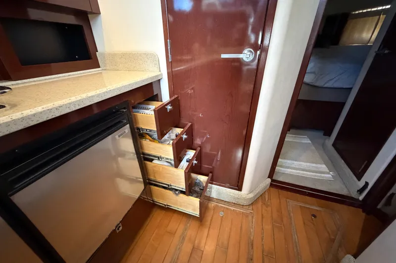 Slide: The Image of Interior of 2010 Sea Ray 390 Sedan Bridge with open drawers and compact fridge. - 64