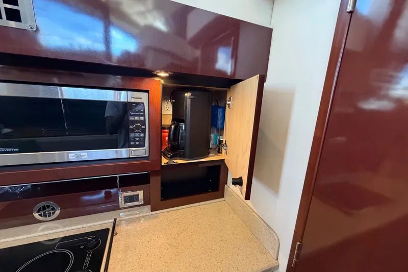 Slide: The Image of Kitchen area of 2010 Sea Ray 390 Sedan Bridge with microwave and open cabinet. - 63
