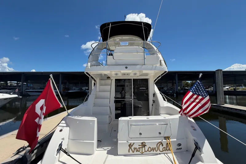 Slide: The Image of 2010 Sea Ray 390 Sedan Bridge yacht docked, featuring dual flags and spacious deck. - 15