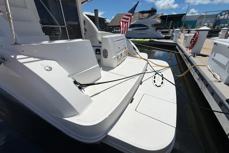 Slide: The Image of 2010 Sea Ray 390 Sedan Bridge docked, featuring spacious deck and American flag. - 18