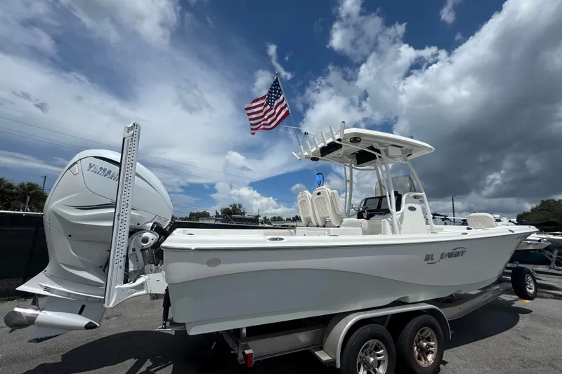 Slide: The Image of 2019 Blue Wave 2800 Pure Hybrid boat with American flag, parked on trailer. - 2