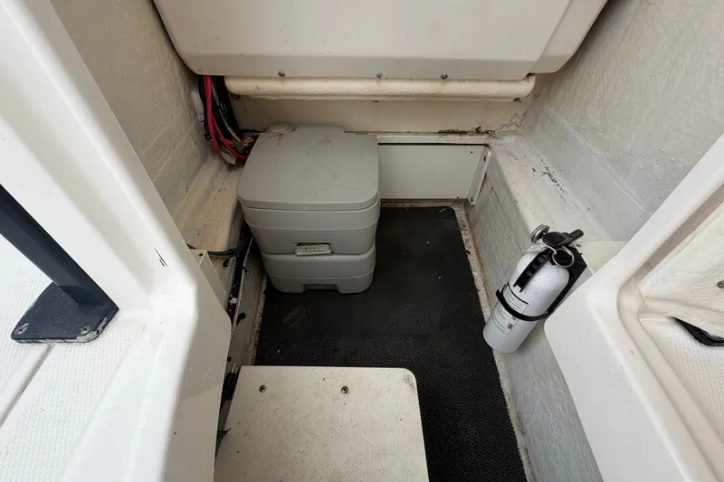 Slide: The Image of 2019 Robalo 226 Cayman boat interior with portable toilet and fire extinguisher. - 57