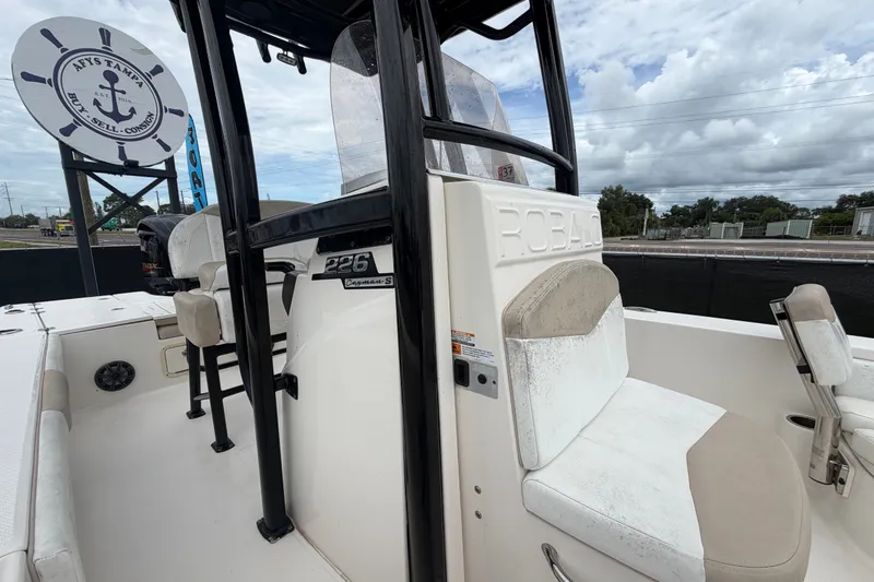 Slide: The Image of 2019 Robalo 226 Cayman boat interior with seating and console, under cloudy sky. - 58