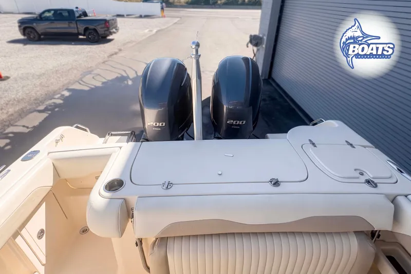 Slide: The Image of 2014 Grady-White Freedom 275 boat with twin 200 horsepower engines, docked near a truck. - 14