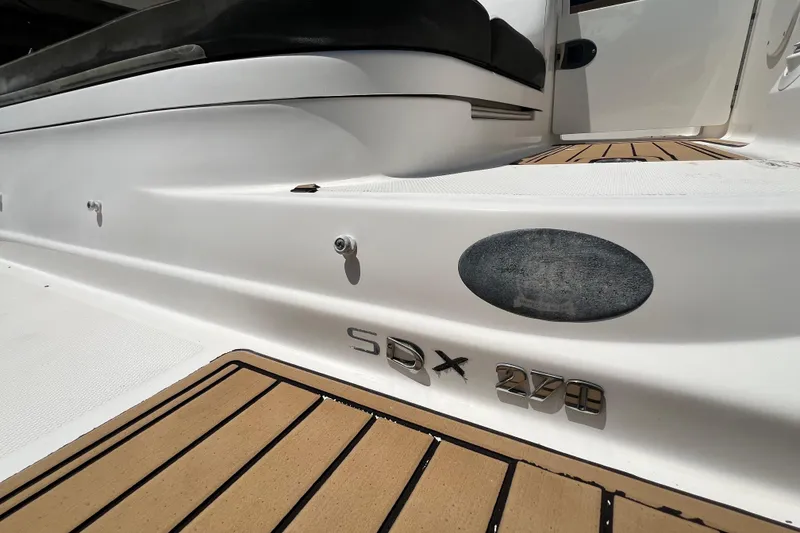 Slide: The Image of 2019 Sea Ray SDX 270 Outboard boat deck with teak flooring and model emblem. - 95