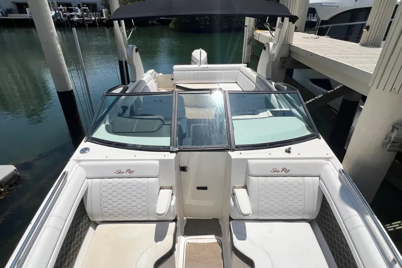 Slide: The Image of 2019 Sea Ray SDX 270 Outboard boat with white seating and black canopy docked by the water. - 55