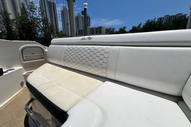 Slide: The Image of 2019 Sea Ray SDX 270 Outboard boat interior with white cushioned seating and urban skyline backdrop. - 39
