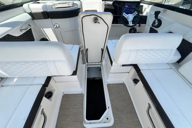 Slide: The Image of 2019 Sea Ray SDX 270 Outboard interior with white seating and open storage compartment. - 101