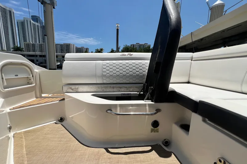 Slide: The Image of 2019 Sea Ray SDX 270 Outboard interior with white seating and urban skyline backdrop. - 37