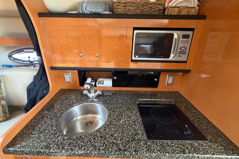 Slide: The Image of 2008 Chaparral Signature 290 boat kitchen with sink, microwave, and stovetop. - 76