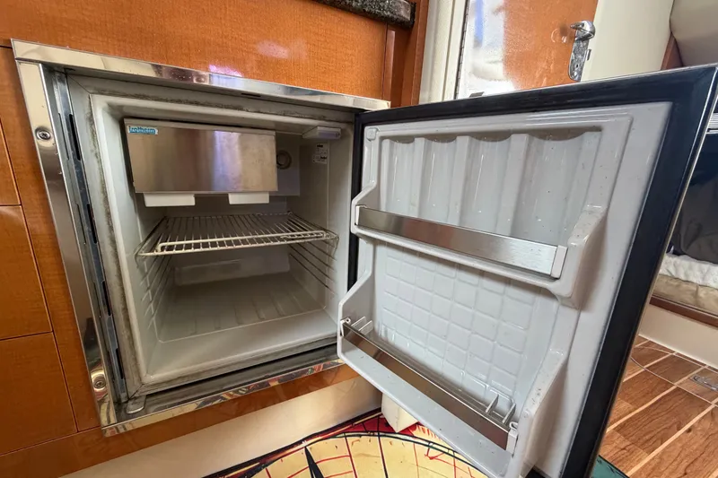 Slide: The Image of Open refrigerator inside 2008 Chaparral Signature 290 boat, showcasing interior shelving. - 79