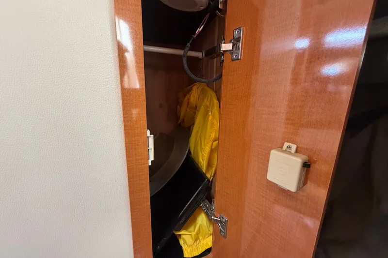Slide: The Image of Open wooden cabinet on 2008 Chaparral Signature 290 boat, revealing yellow rain gear inside. - 94