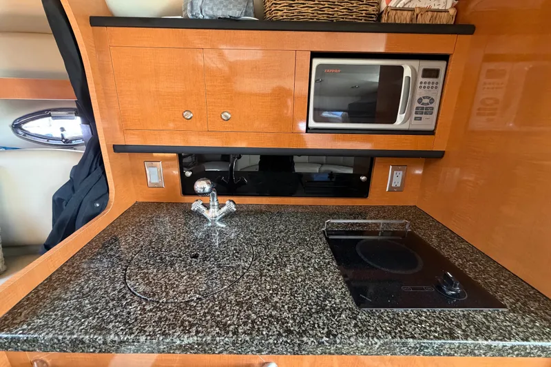 Slide: The Image of 2008 Chaparral Signature 290 boat kitchen with granite countertop, microwave, and electric stove. - 75