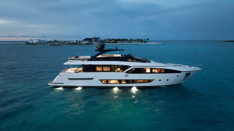 Slide: The Image of Luxurious 2020 Riva 90 Argo yacht illuminated on serene ocean waters at dusk. - 7