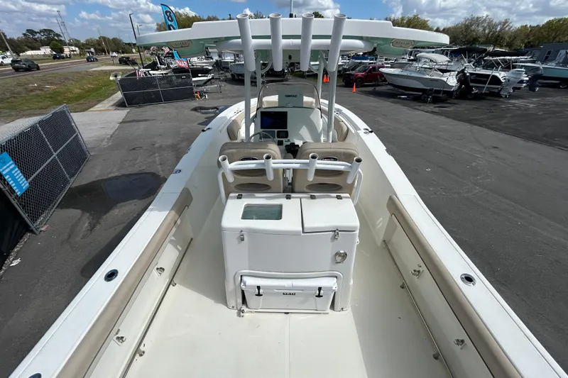 Slide: The Image of 2018 NauticStar 28 XS boat interior with helm and seating, docked outdoors. - 13