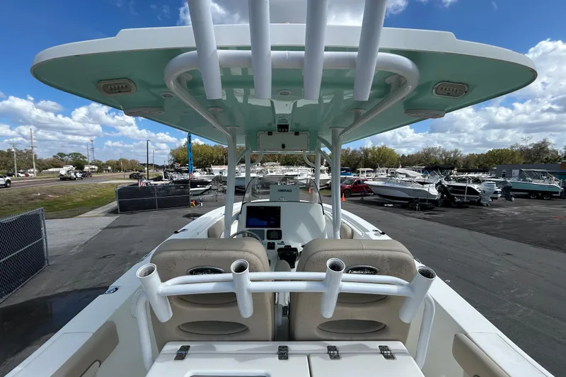 Slide: The Image of 2018 NauticStar 28 XS boat interior with rod holders, parked in a marina under blue skies. - 15