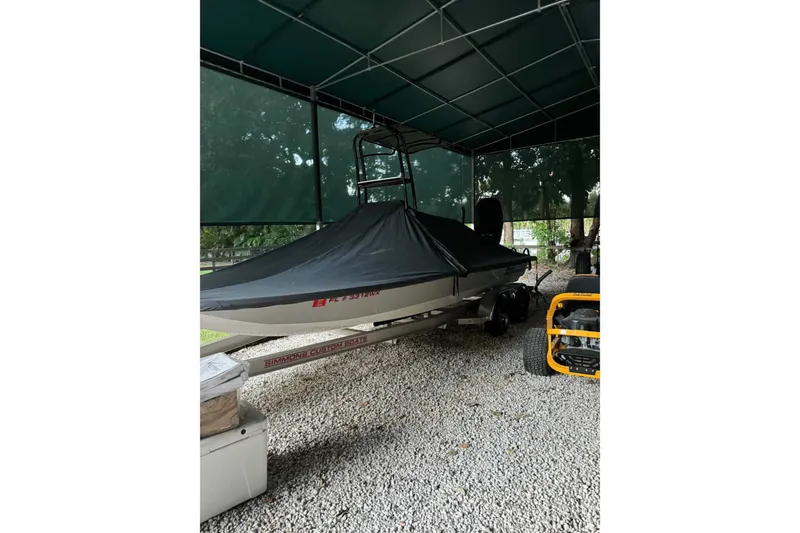 Slide: The Image of 2023 SCB S22 boat covered and parked under a canopy on gravel. - 7