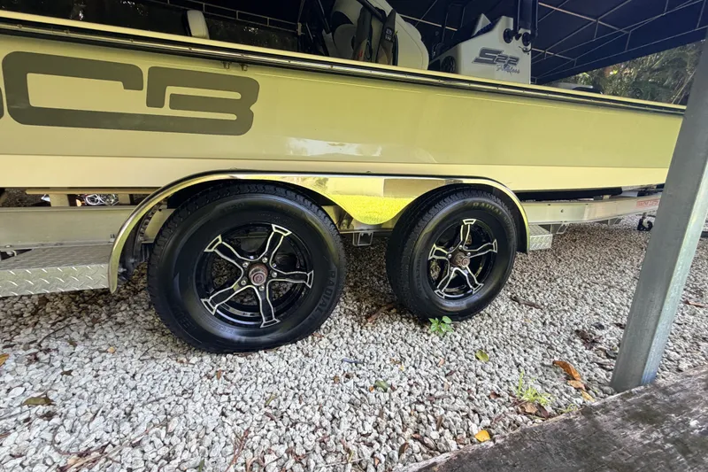 Slide: The Image of 2023 SCB S22 boat trailer with dual black alloy wheels on gravel. - 14