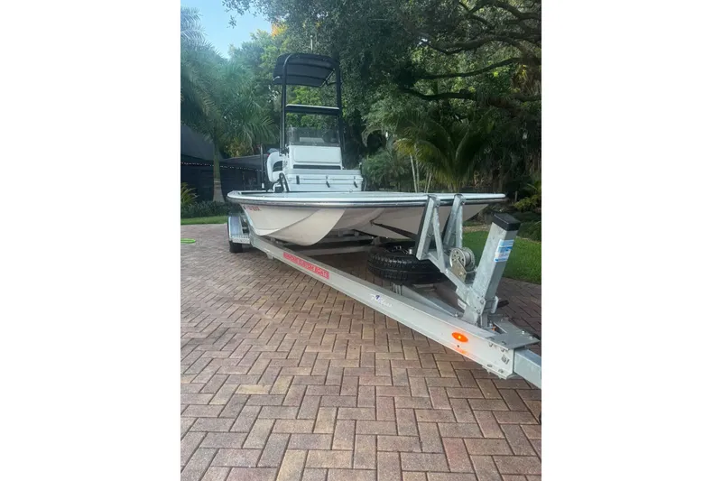 Slide: The Image of 2023 SCB S22 boat on trailer, parked on brick driveway, surrounded by lush greenery. - 1